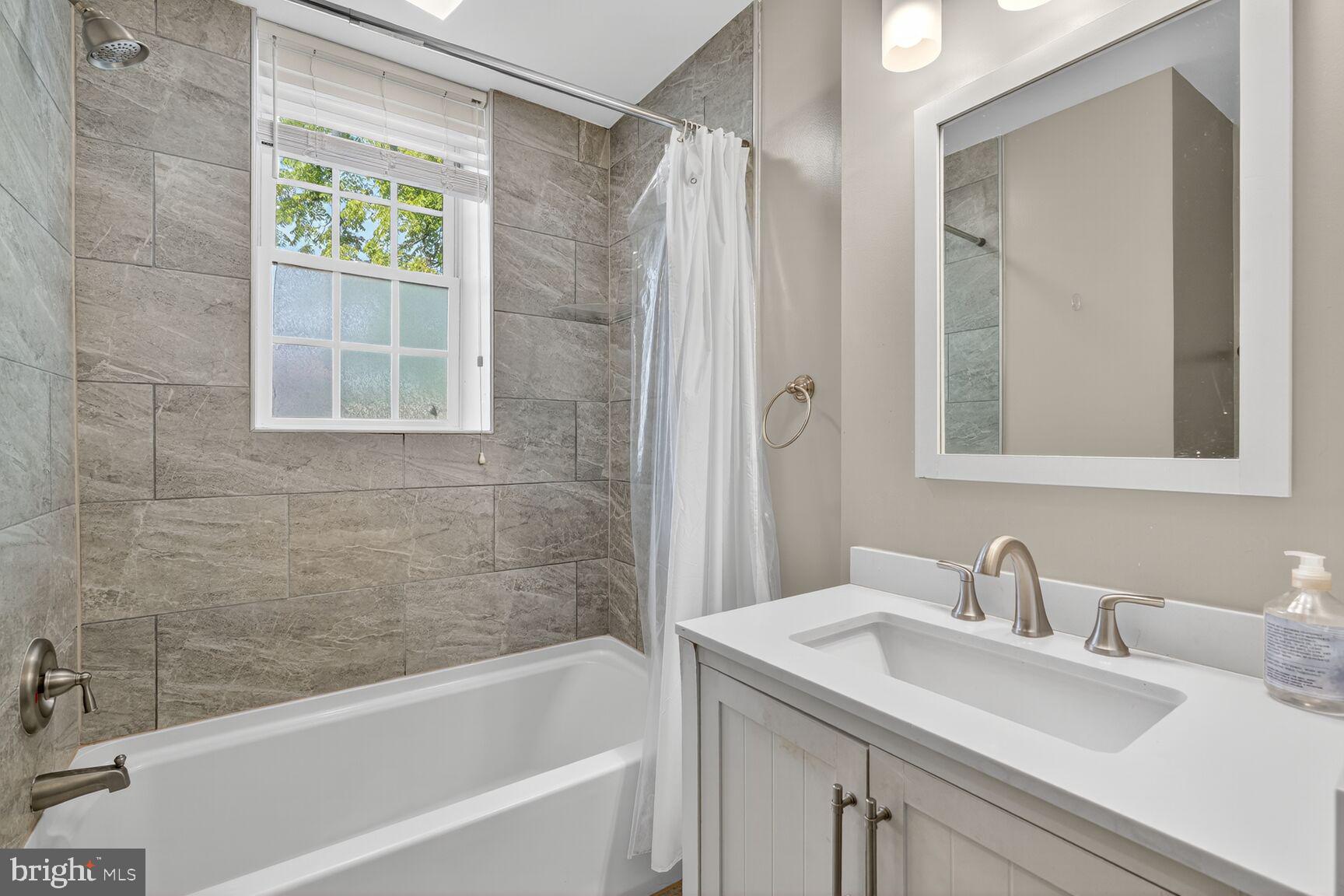 133 7th Street Southeast, Unit 10 Washington, DC 20003 - Photo 12 of 14 a bathroom with a granite countertop sink and a bathtub