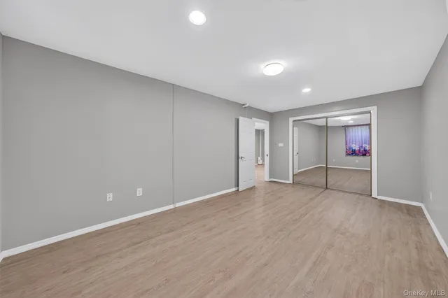 a view of an empty room with wooden floor and closet