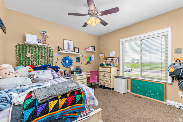 5702 950 North Ogden, UT 84404 - Photo 23 of 36 Spacious bedroom featuring light brown carpeting and walls, a ceiling fan with integrated lighting, and a large window with white blinds and trim