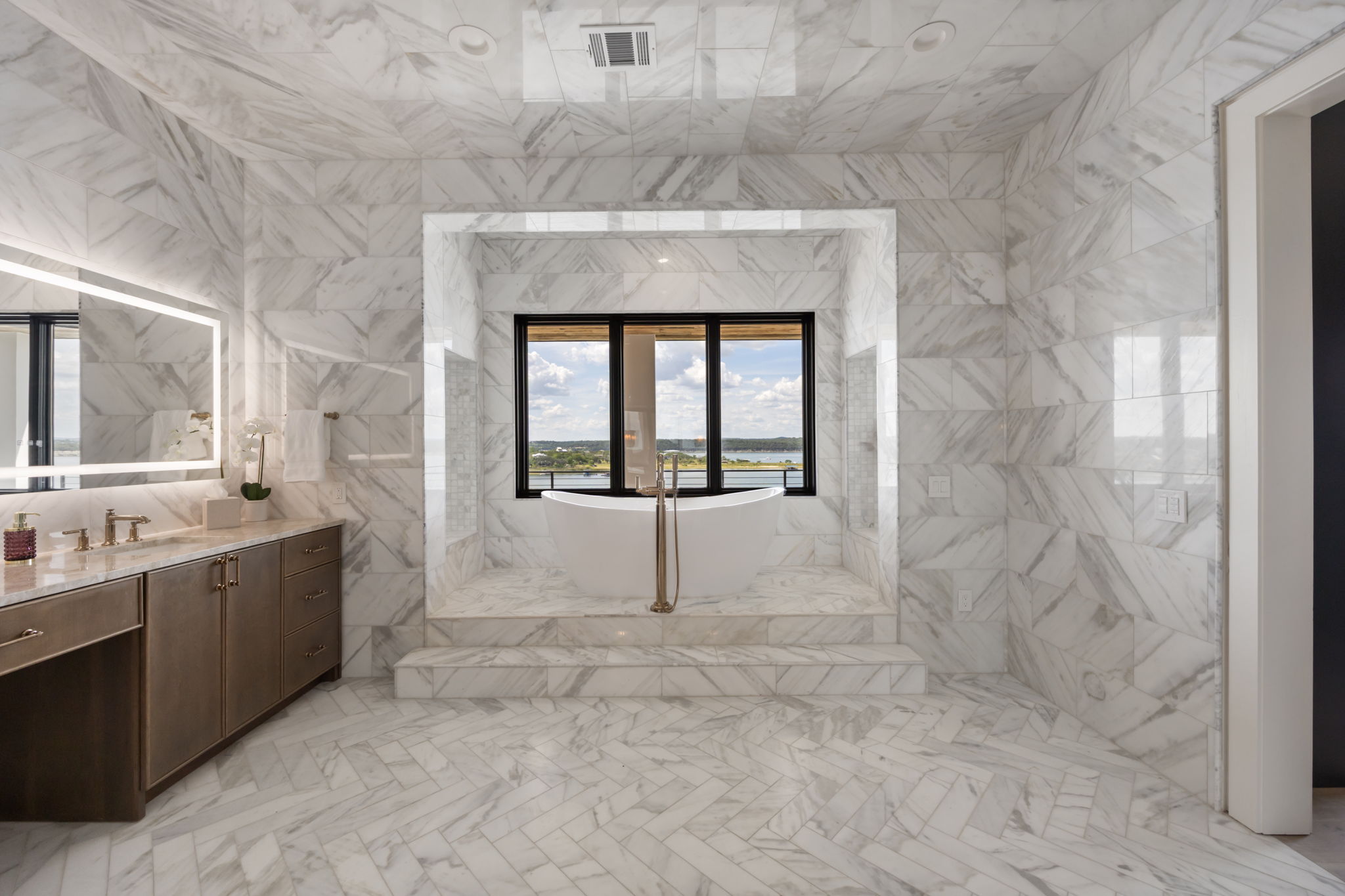 1496 Buffalo Gap Road Lakeway, TX 78734 - Photo 21 of 37 A lavish bath features a soaking tub and a vanity with an illuminated mirror, all surrounded by luxurious marble.