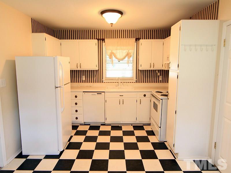 4609 Revere Road Durham, NC 27713 - Photo 4 of 12 a kitchen with a checkered floor and white cabinets