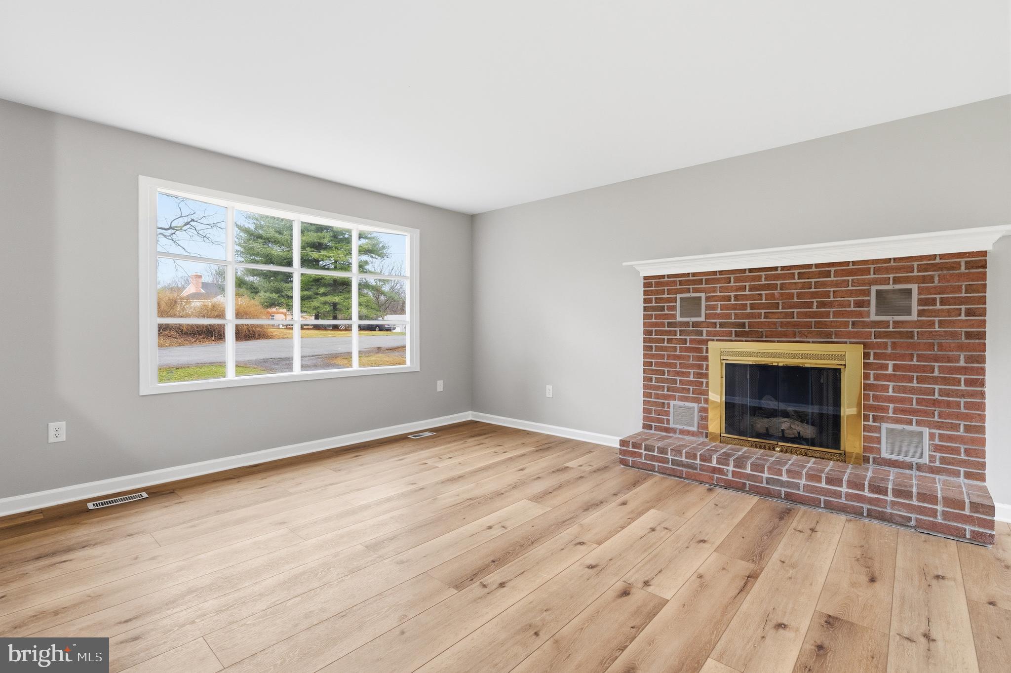404 Weeping Willow Road Falling Waters, WV 25419 - Photo 6 of 24 an empty room with wooden floor a fireplace and windows
