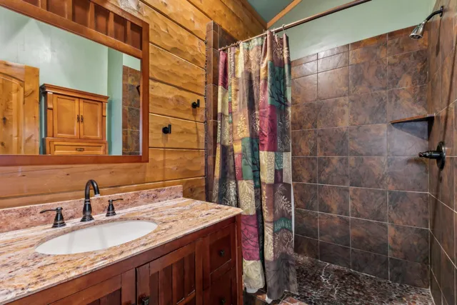 a bathroom with a granite countertop shower a sink and a mirror