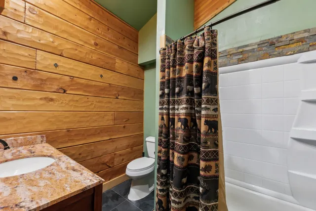 a bathroom with a granite countertop toilet and a shower