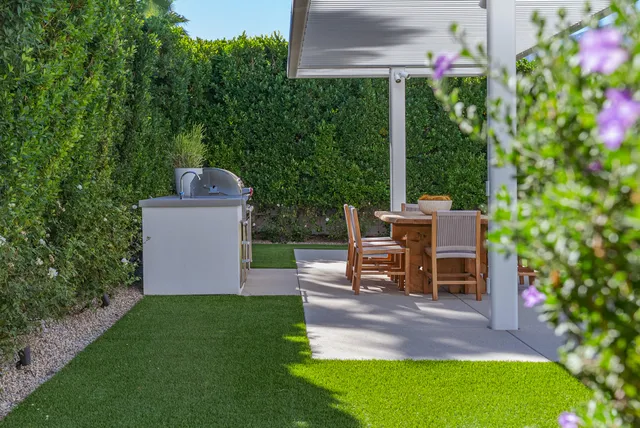 a view of a patio with table and chairs potted plants and large tree