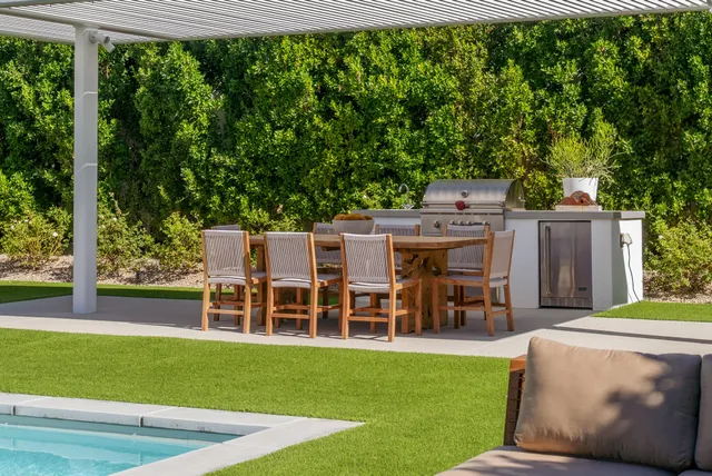 a view of a patio with couches table and chairs under an umbrella with a big yard