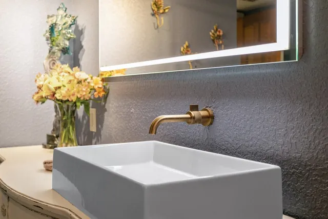 a bathroom with a sink a mirror and a potted plant