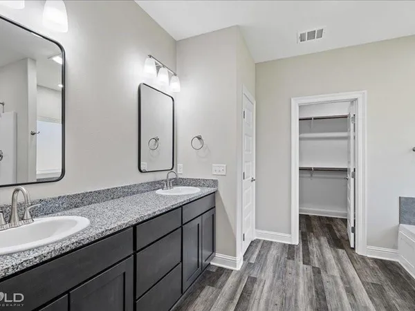 a bathroom with a granite countertop double vanity sink and mirror
