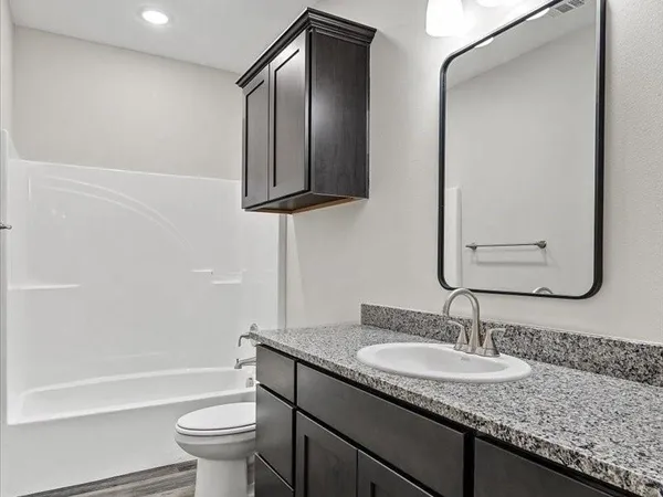 a bathroom with a granite countertop sink toilet and mirror