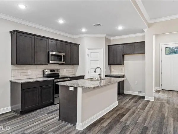 a kitchen with stainless steel appliances granite countertop a stove top oven a sink dishwasher a refrigerator and a microwave oven with wooden floor