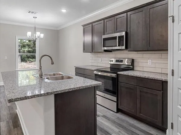 a kitchen with granite countertop stainless steel appliances a sink cabinets and wooden floor