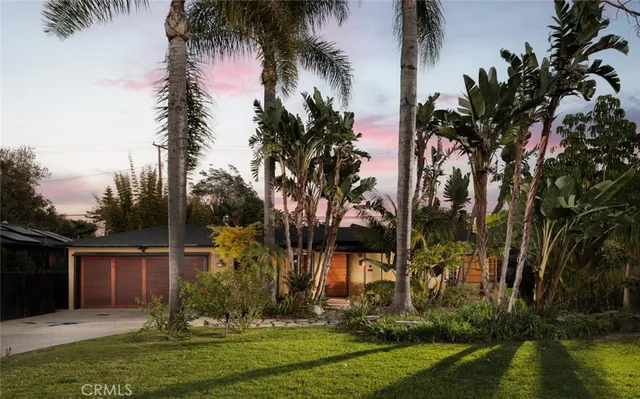 front view of house with a yard and palm trees