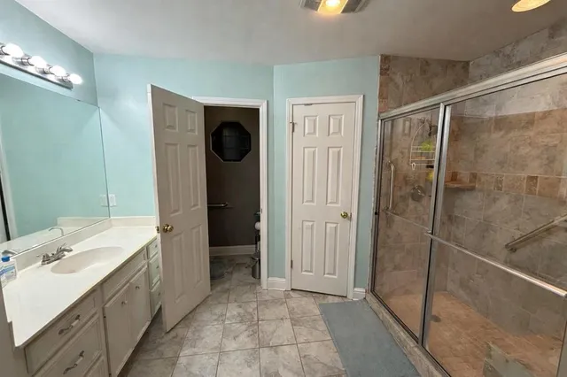 a bathroom with a double vanity sink a toilet and shower