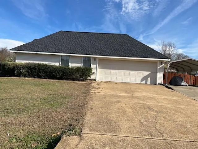 a front view of house with yard and trees in the background