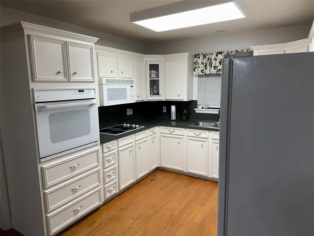 a kitchen with granite countertop white cabinets and white appliances