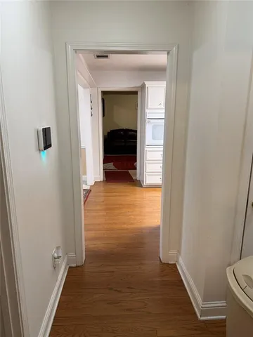 a view of a hallway with wooden floor and a bathroom