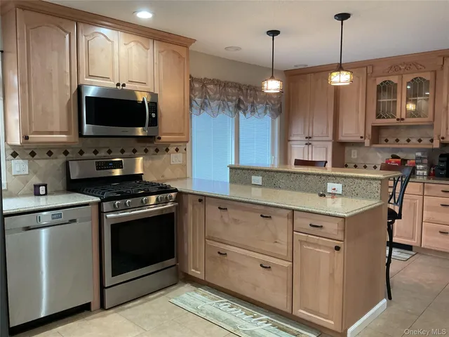 a kitchen with stainless steel appliances granite countertop a sink a stove a microwave a counter top space and cabinets