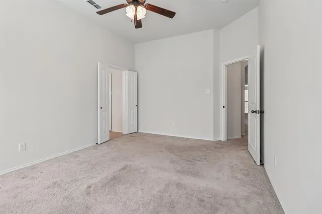 an empty room with chandelier fan and windows