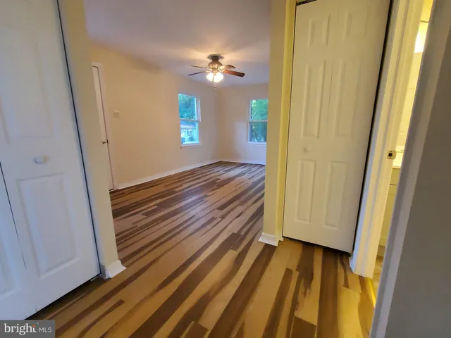 a view of a hallway with wooden floor and closet