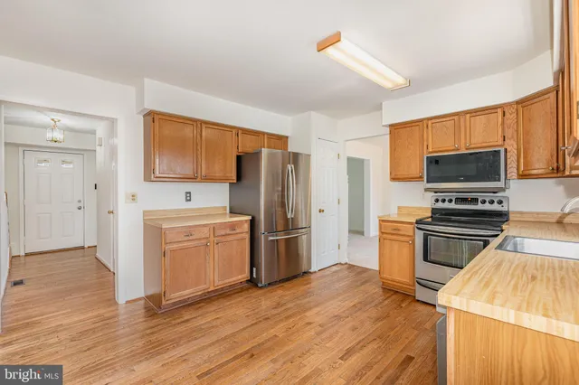 a kitchen with a refrigerator stove and wooden floor