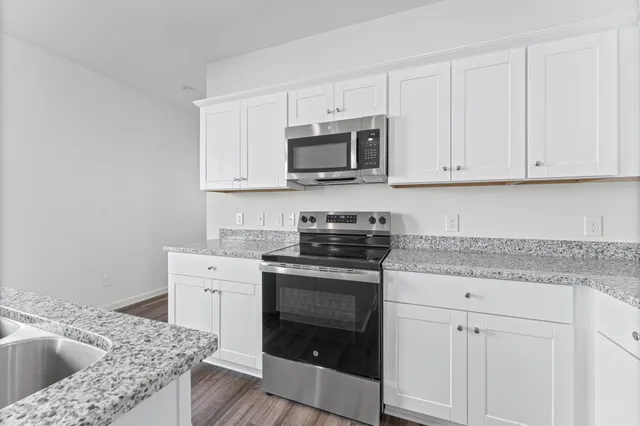 a kitchen with granite countertop a sink stove and cabinets