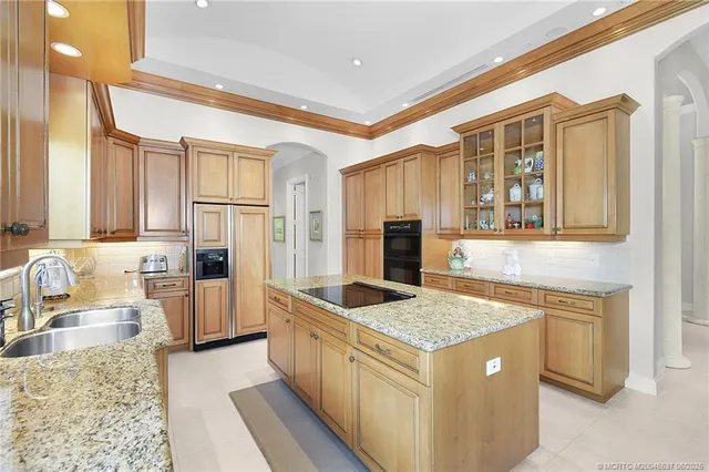 a kitchen with granite countertop a sink stove and refrigerator