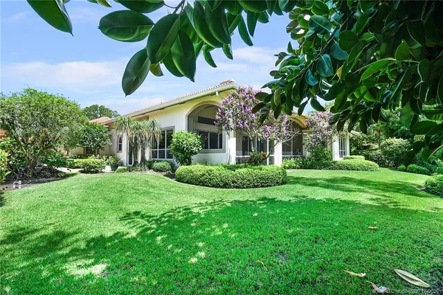 a view of a white house with a big yard and potted plants