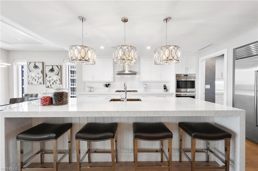 13915 Old Coast Road, Unit 1706 Naples, FL 34110 - Photo 5 of 49 a kitchen with stainless steel appliances kitchen island granite countertop a table and chairs in it