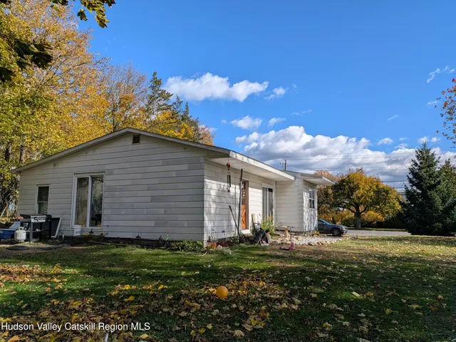 a backyard of a house with plants and large tree