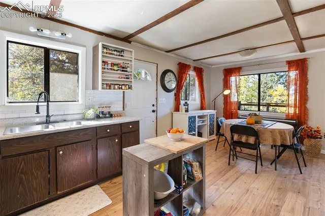 a open dining room with stainless steel appliances granite countertop a sink a stove a dining table and chairs with wooden floor