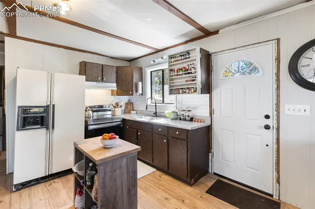 a kitchen with a refrigerator a sink and wooden floor