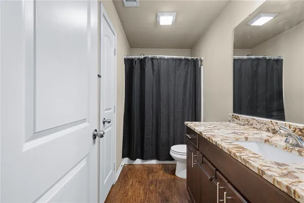 a bathroom with a granite countertop sink a toilet a mirror and shower