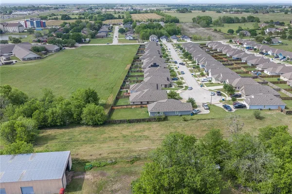 an aerial view of residential houses with outdoor space and trees