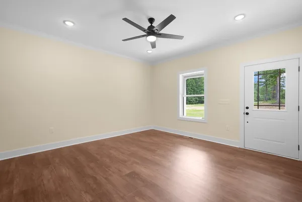 an empty room with wooden floor and a ceiling fan