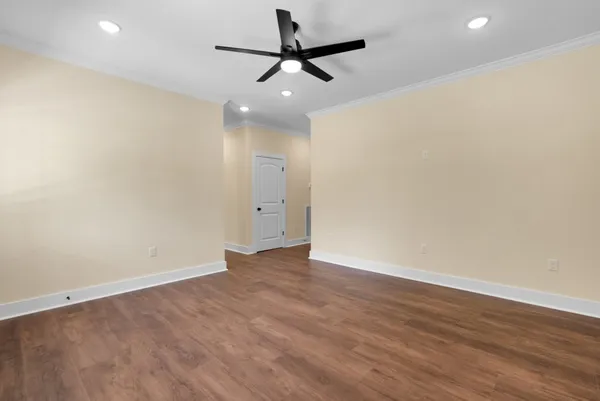 a view of an empty room with wooden floor fireplace and a window