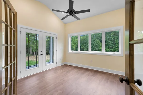 an empty room with wooden floor fan and windows