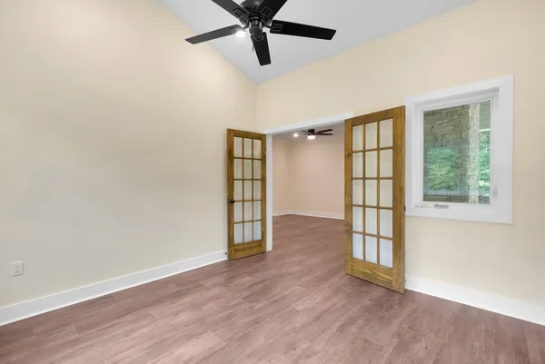 a view of an empty room with a window and wooden floor