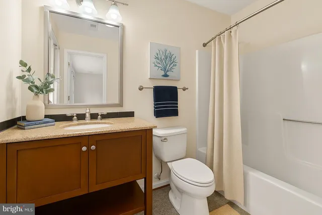a bathroom with a granite countertop toilet sink and mirror