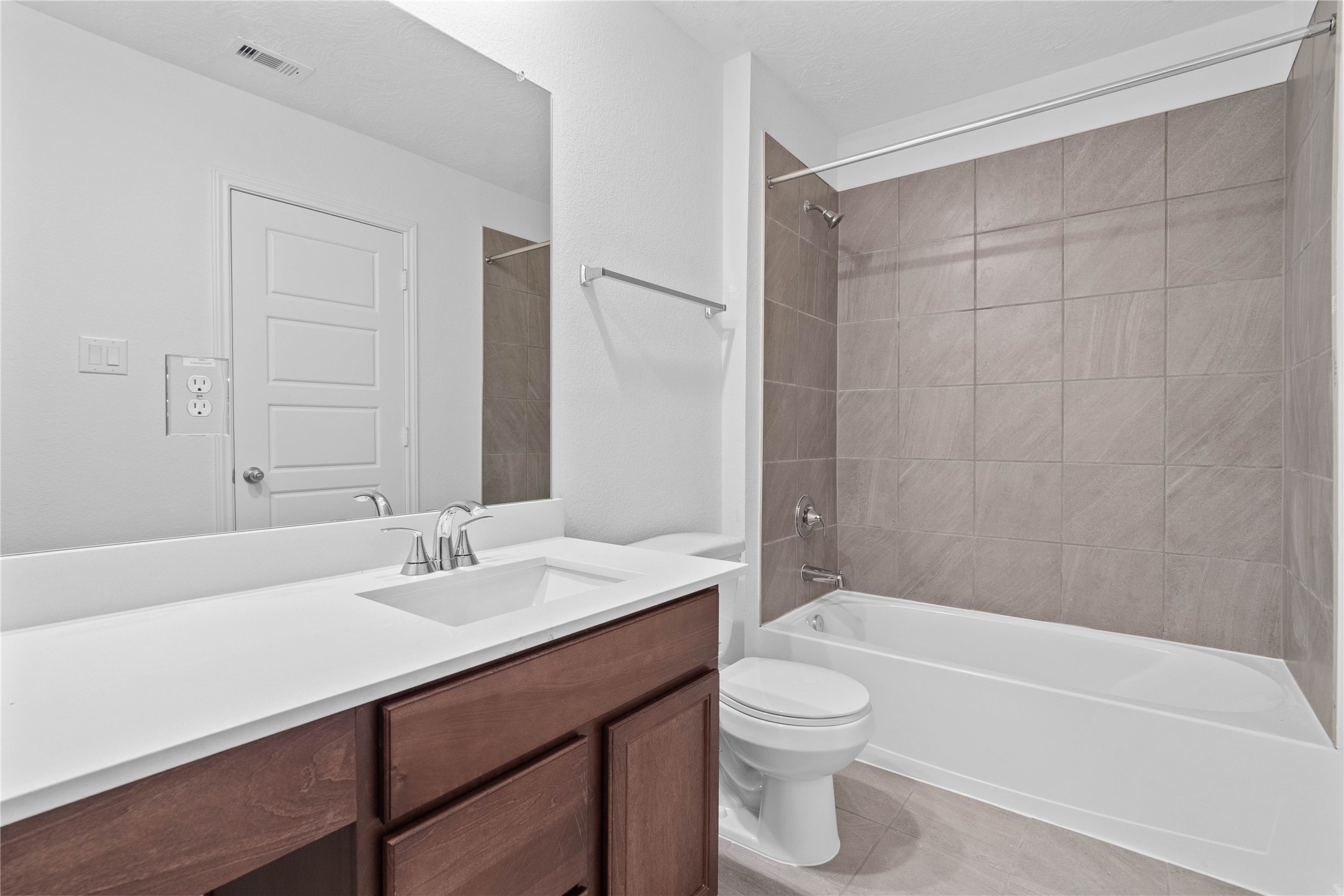 7210 Brooklea Road Beasley, TX 77417 - Photo 23 of 32 The secondary bathroom offers tile flooring, a tub/shower combination with a stylish tile surround, rich stained wood cabinetry with added knee space and elegant light countertops, a mirror, and sleek fixtures with modern finishes.