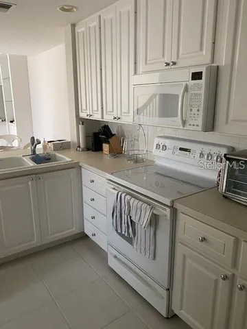 a kitchen with white cabinets and white appliances