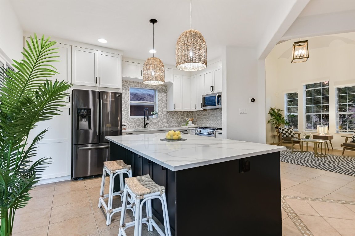 7711 Stephany Taylor Drive Austin, TX 78745 - Photo 5 of 23 a kitchen with stainless steel appliances kitchen island granite countertop a table chairs in it and wooden floors
