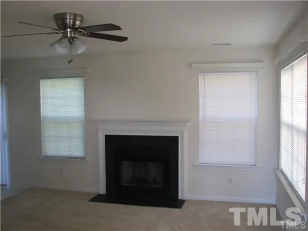 an empty room with windows and a fireplace