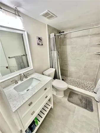 a bathroom with a granite countertop sink a toilet a mirror and shower