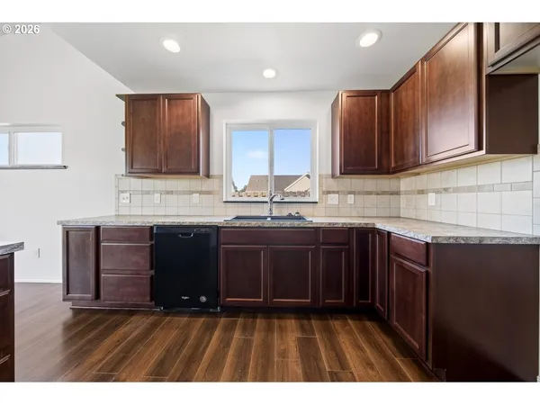 a kitchen with granite countertop wooden cabinets a sink and dishwasher