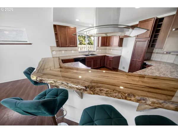 a kitchen with stainless steel appliances kitchen island granite countertop a sink dishwasher and granite countertops with wooden floor