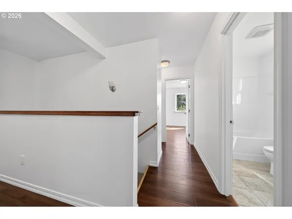 a view of an empty room with wooden floor and closet