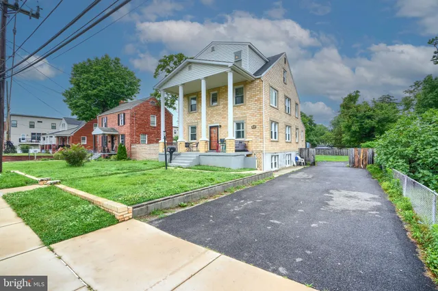 a view of a white house with a yard and potted plants