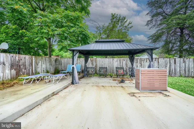 a view of a patio with table and chairs with wooden fence and large trees