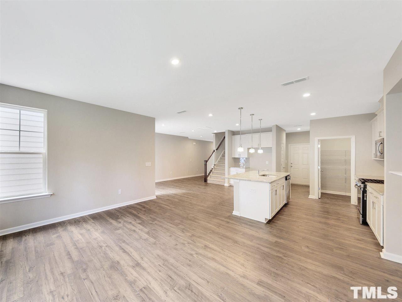 1605 Brussels Drive Apex, NC 27502 - Photo 4 of 17 a view of an empty room and kitchen with wooden floor