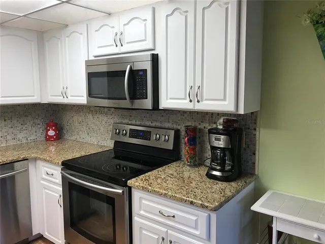 a kitchen with granite countertop white cabinets and stainless steel appliances